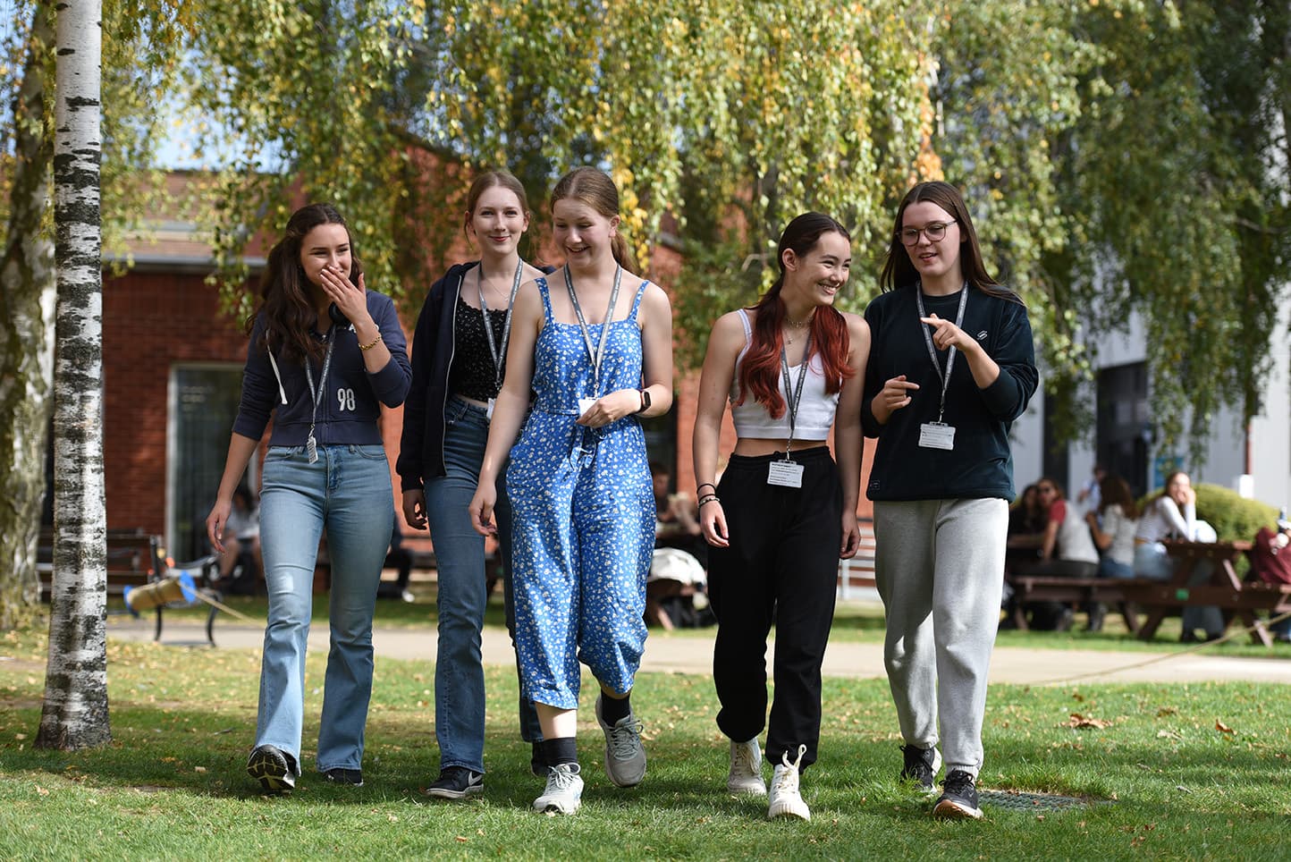 Five students walking on the grass