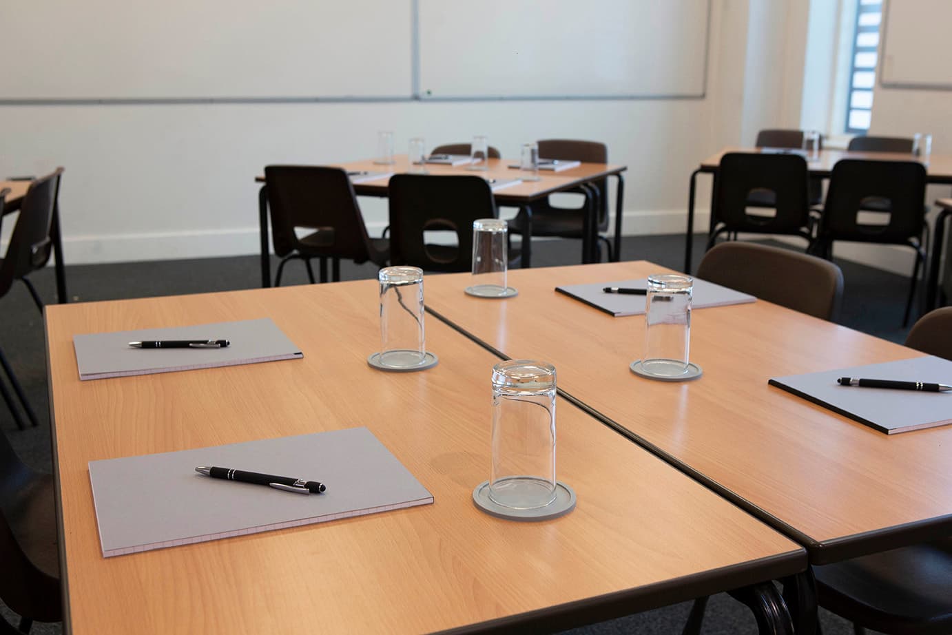 tables set up with notebooks, pens and glasses