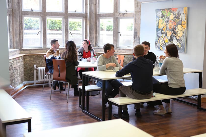 People sitting around tables in the Hub
