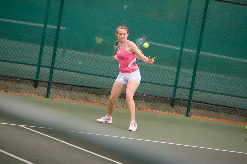 Student playing tennis on one of the outdoor tennis courts